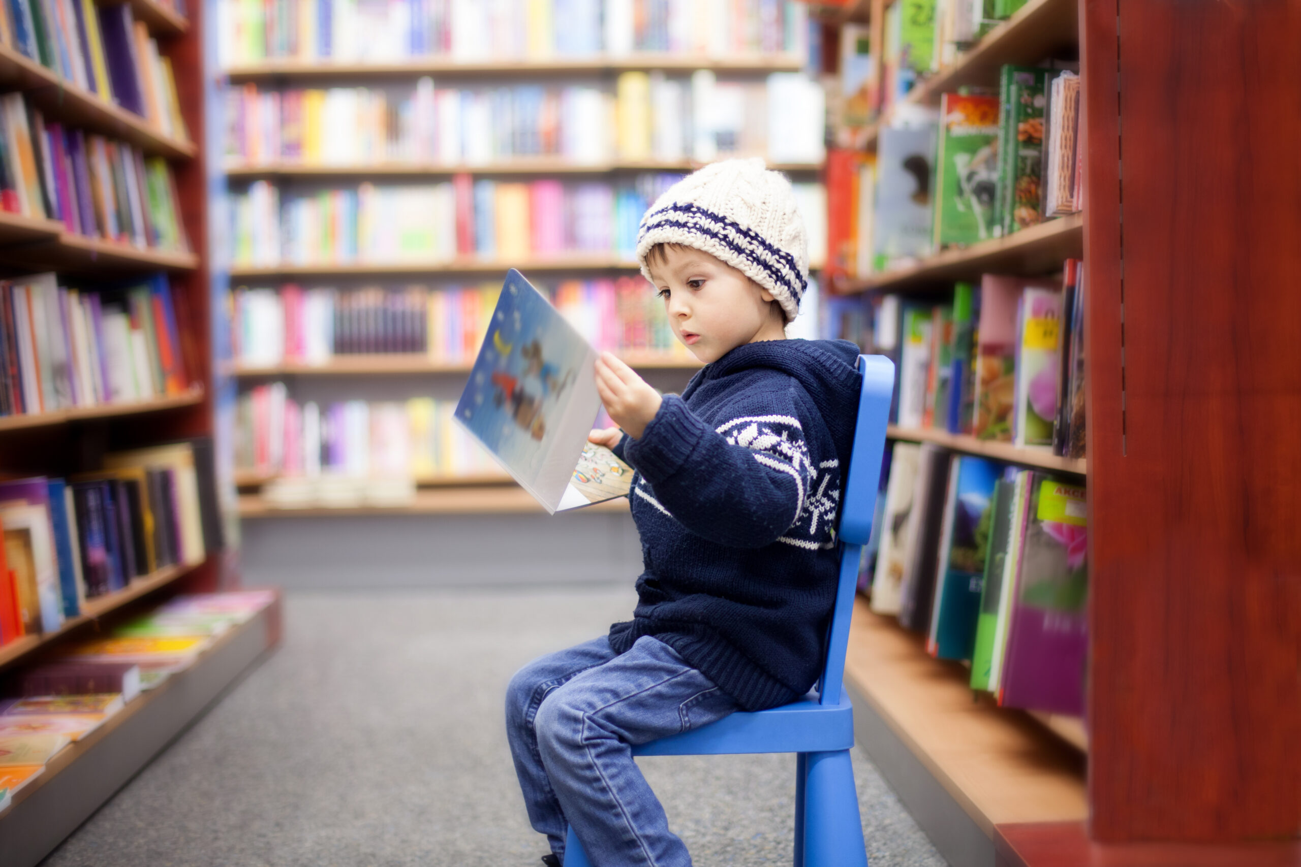 Adorable,Little,Boy,,Sitting,In,A,Book,Store,,Looking,At